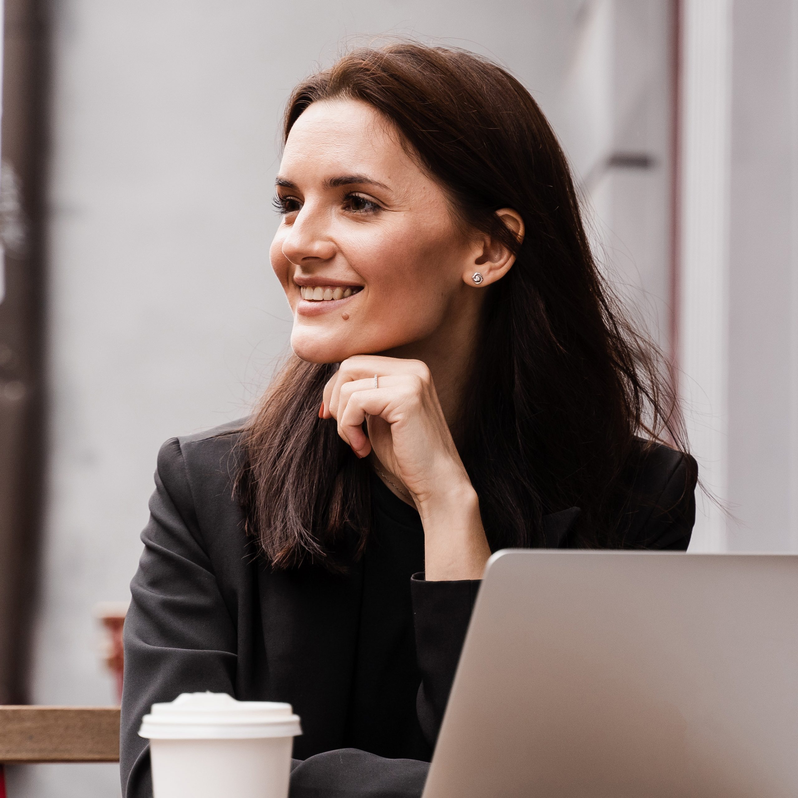 Cheerful surprised woman smiling and looking at amount of income earnings in online casino and rejoicing outside. Shocked girl is winning bet in online casino and sitting with laptop in cafe outdoor